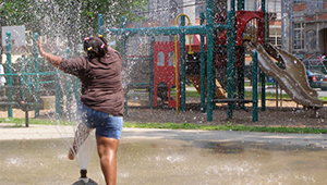 Girl splashing through spray pool at urban park