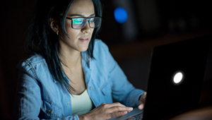 Woman sitting at table typing on laptop 