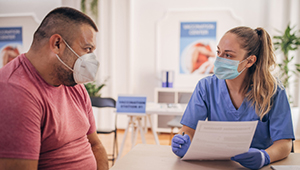 Male patient with mask talking with Nurse wearing mask