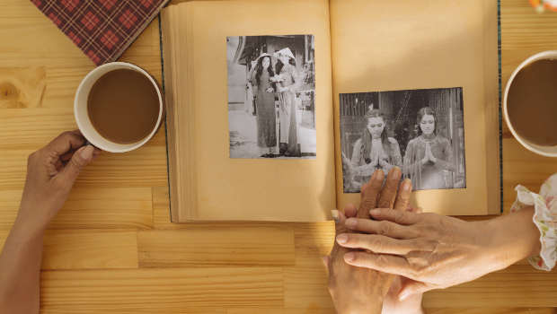 Photo album, hands and a cup of coffee