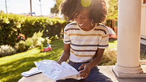 Woman siting on porch outside reading mail