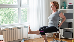 Woman in home sitting doing a leg raise exercise